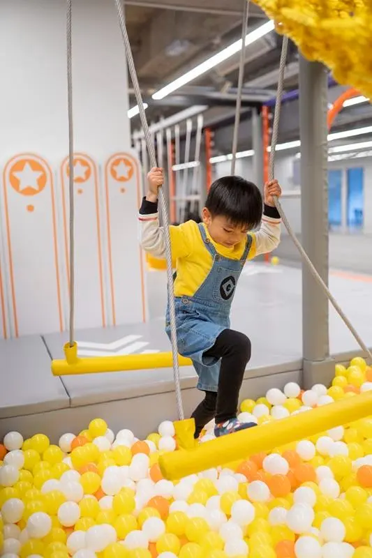 A child crossing the rope bridge over the ball pit at MosKiddo